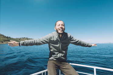 Peru, Titicaca lake, Taquile, happy man with outstretched arms on a boat - GEMF01552