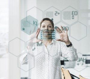 Businesswoman touching glass pane with data in office - UUF10234