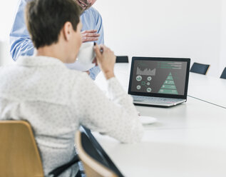 Businessman and businesswoman discussing data on laptop - UUF10245