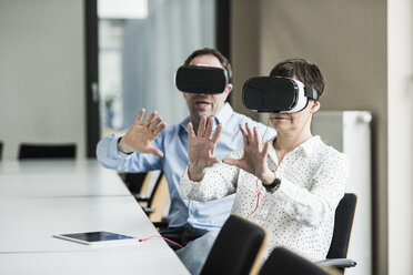 Businessman and businesswoman wearing VR glasses in office - UUF10286