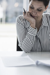 Businesswoman reading document at desk in office - UUF10292