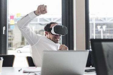 Businessman with VR glasses at desk in office - UUF10301