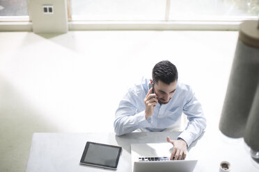 Young businessman working in office, using mobile devices - ZEF13271