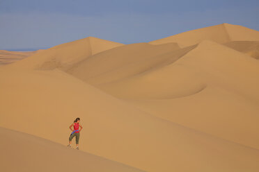 Woman standing on sand dunes in desert - DSGF01661