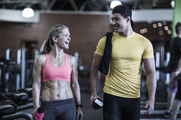 Glücklicher junger Mann und Frau im Gespräch im Fitnessstudio - ZEF13333