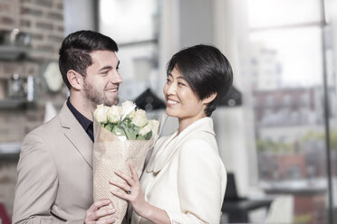 Man handing over roses to woman at home - ZEF13341