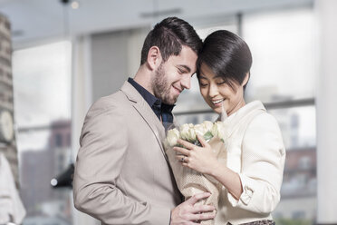 Man handing over roses to woman at home - ZEF13342