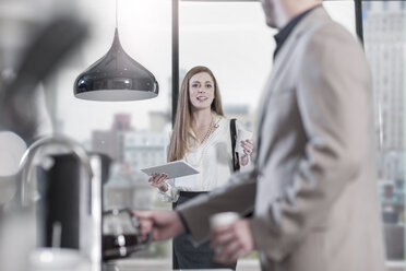 Woman with digital tablet talking to man preparing coffee - ZEF13346