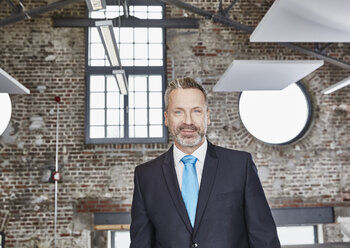 Portrait of confident businessman in a loft - FMKF03654