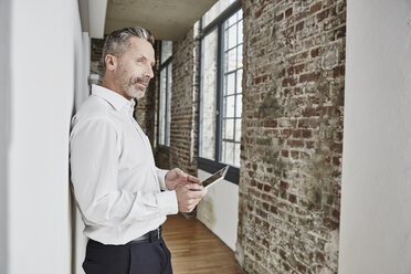 Businessman holding tablet on modern office floor - FMKF03681