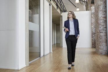 Businesswoman walking on modern office floor - FMKF03697