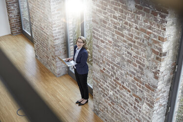 Happy businesswoman on modern office floor using laptop - FMKF03700