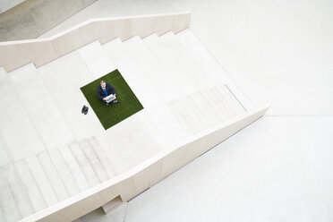 Top view of businesssman on stairs using laptop - FMKF03710