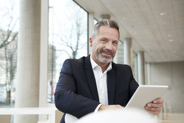 Porträt eines lächelnden Geschäftsmannes mit Tablet - FMKF03722