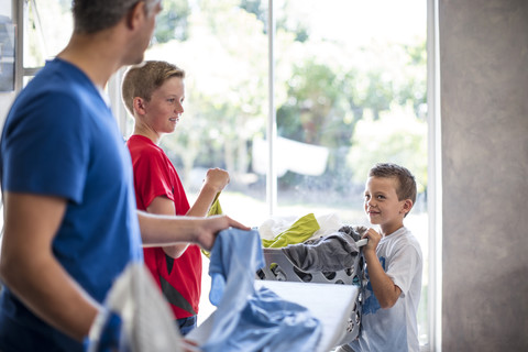 Boys helping father with chores carrying laundry basket stock photo