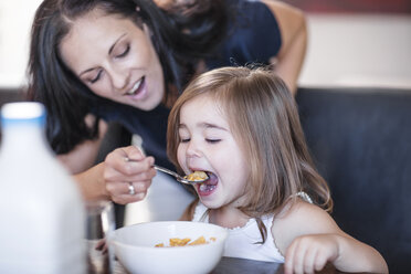 Mutter füttert Tochter am Tisch mit Frühstücksflocken - ZEF13426