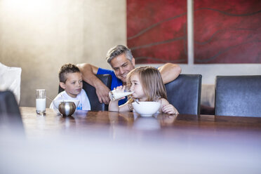 Happy father with children seated having breakfast at table - ZEF13432