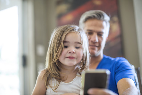 Vater und Tochter teilen sich ein Mobiltelefon, lizenzfreies Stockfoto