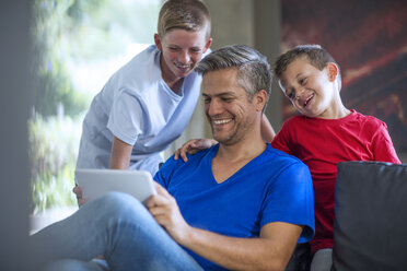 Kinder schauen mit ihrem Vater auf ein digitales Tablet - ZEF13446