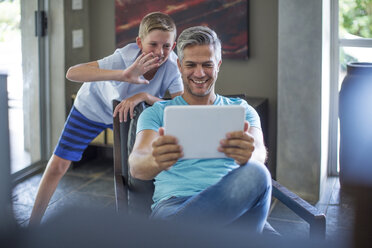 Glücklicher Vater und Sohn mit digitalem Tablet zu Hause - ZEF13449