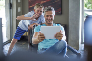 Happy father and son with digital tablet at home - ZEF13449