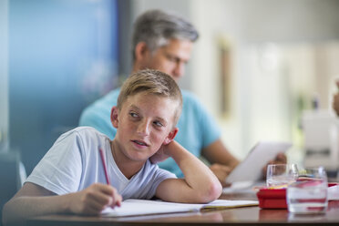 Junge macht Hausaufgaben mit Vater im Hintergrund - ZEF13468