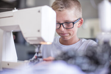 Junge mit Brille arbeitet an einer Nähmaschine - ZEF13471