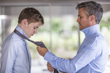 Vater hilft Sohn beim Binden seiner Krawatte - ZEF13481