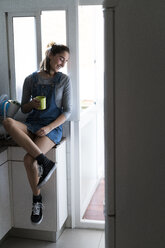 Entspannte junge Frau, die zu Hause einen Kaffee trinkt - KKAF00580