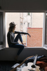 Junge Frau mit Hut sitzt im Fensterrahmen - KKAF00631