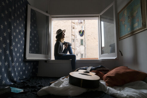 Junge Frau mit Hut sitzt im Fensterrahmen - KKAF00632