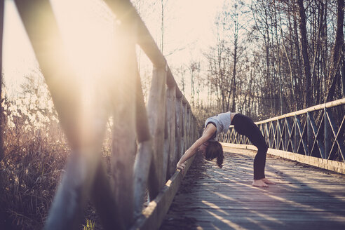 Frau macht Rad Pose auf einer Brücke - SIPF01504