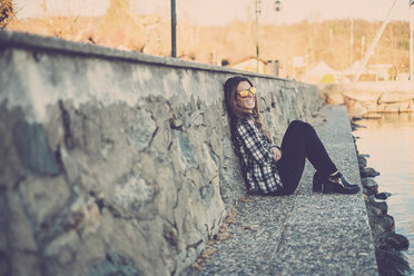 Woman sitting outdoors, leaning on a wall - SIPF01507