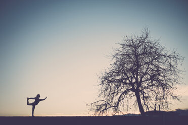 Silhouette einer Frau, die Yoga in der Natur praktiziert - SIPF01513