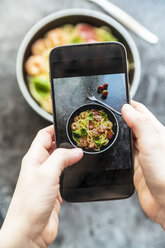 Hände, die mit dem Smartphone ein Foto von Spaghetti mit Garnelen, Tomaten und Basilikum machen - SARF03270