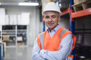 Porträt eines Mannes in einer Fabrikhalle mit Sicherheitsweste und Schutzhelm - DIGF01610