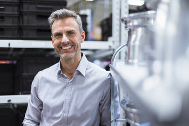 Portrait of smiling businessman in factory hall - DIGF01613