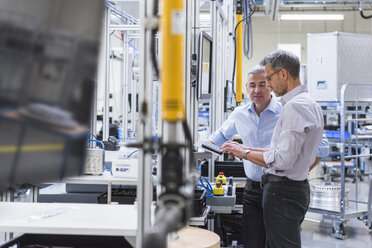 Two businessmen in modern factory hall using computer - DIGF01614