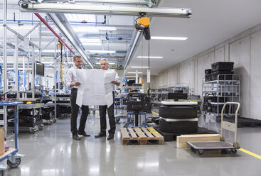 Zwei Geschäftsleute besprechen in einer Fabrikhalle einen Bauplan - DIGF01621