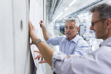 Two businessmen discussing construction plan at concrete wall - DIGF01629