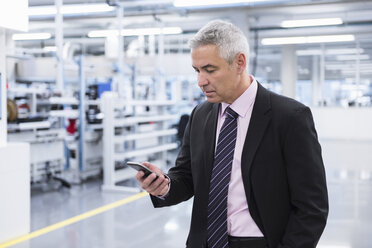 Manager at shop floor of a factory, using smart phone - DIGF01638