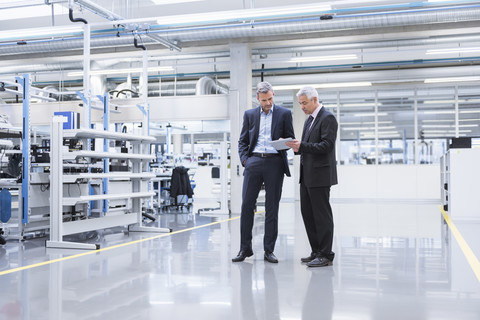 Zwei Manager bei einer Besprechung in der Werkstatt einer Fabrik, lizenzfreies Stockfoto