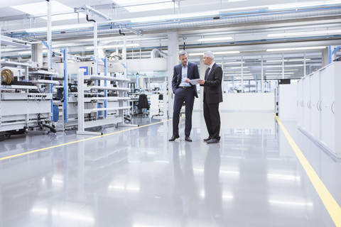 Zwei Manager bei einer Besprechung in der Werkstatt einer Fabrik, lizenzfreies Stockfoto