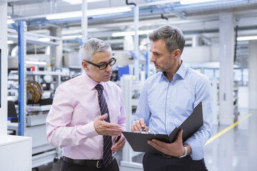 Zwei Manager diskutieren in der Fabrikhalle eines Unternehmens - DIGF01660