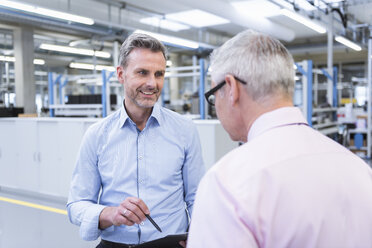 Zwei Manager diskutieren in der Fabrikhalle eines Unternehmens - DIGF01661