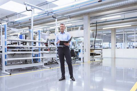 Manager mit Akten, die durch die Fabrik gehen, lizenzfreies Stockfoto