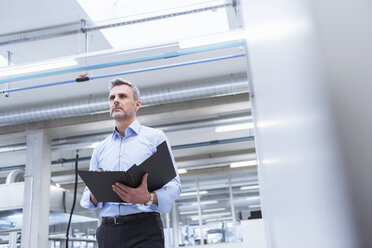 Manager with files walking through factory - DIGF01668