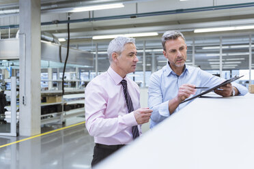 Zwei Manager diskutieren in der Fabrikhalle eines Unternehmens - DIGF01671