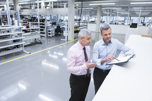 Zwei Manager diskutieren in der Fabrikhalle eines Unternehmens - DIGF01672