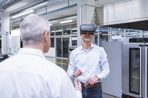 Zwei Manager stehen in einem Unternehmen und benutzen eine VR-Brille, lizenzfreies Stockfoto